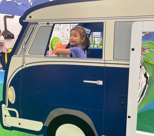 A young girl playing in a play system from IKC in the form of a van