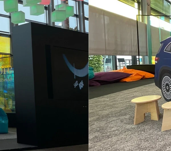 Kinderhoek in Mercedes-Benz showroom met interactieve speelobjecten, waaronder een blauw Mercedes-auto speelmeubel met wandspel, kleurrijke zitzakken en speeltafels, omgeven door grote glazen ramen en modern interieur.