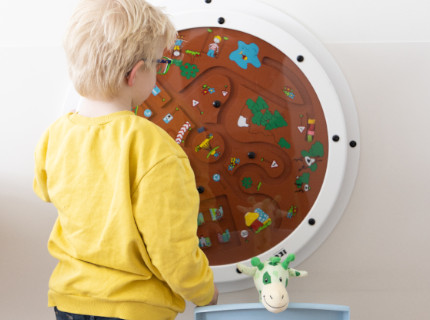 Kind speelt met wandspeelbord in de wachtkamer van het ziekenhuis