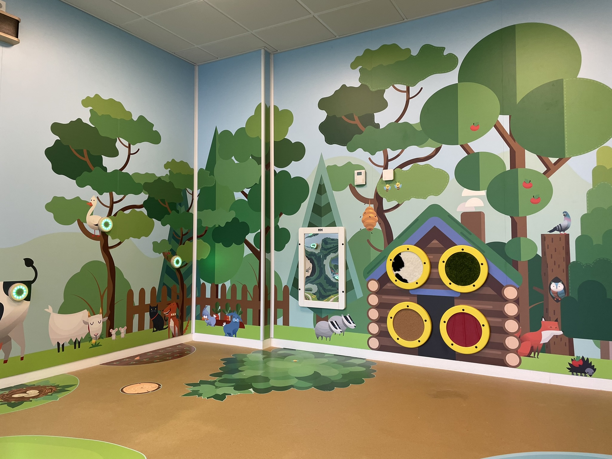 Interactive forest-themed children’s play corner with tactile wall elements, animal illustrations and activity panels