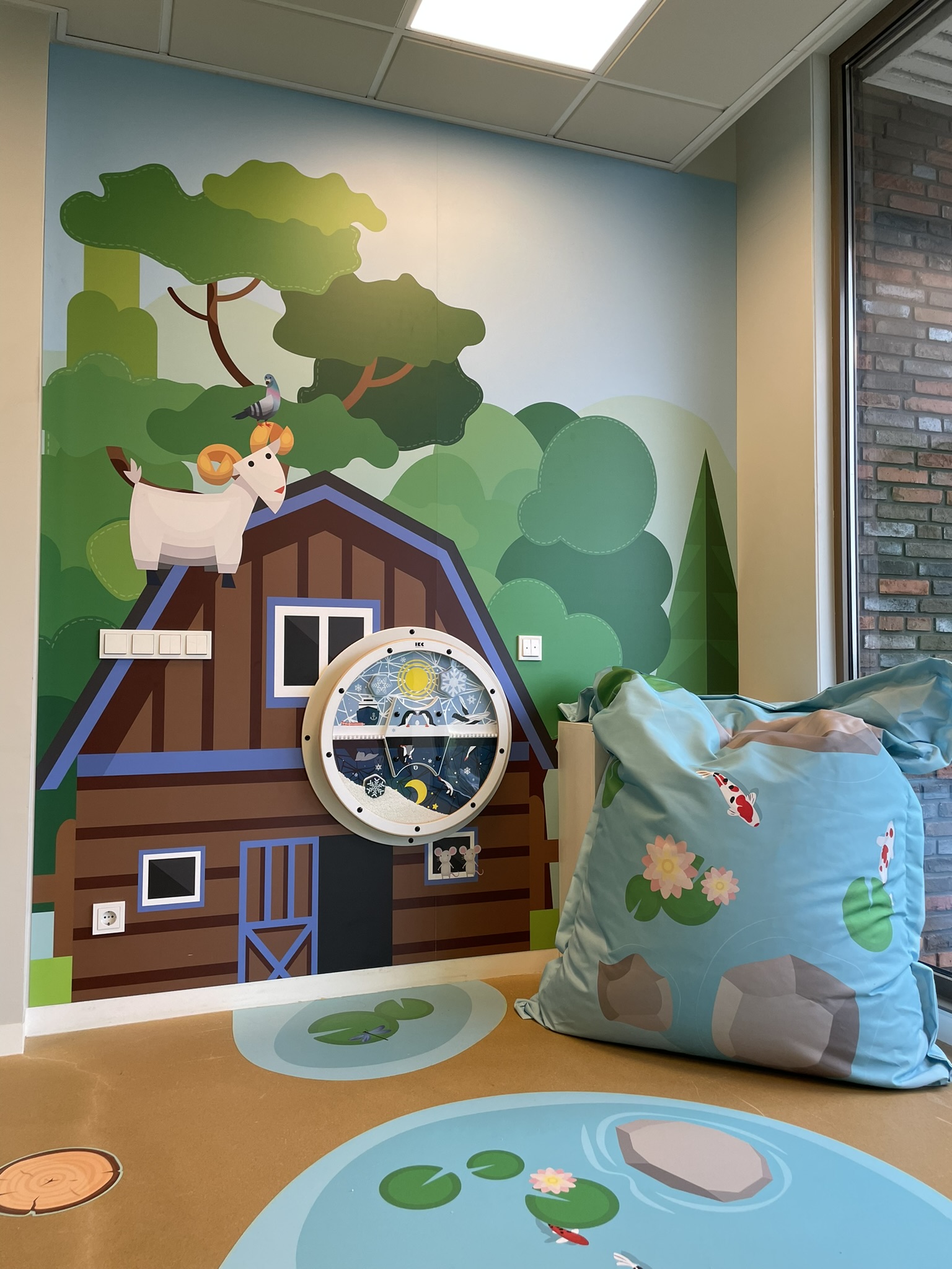 Children’s indoor farm-themed play corner with interactive wall panel, nature illustrations and soft seating