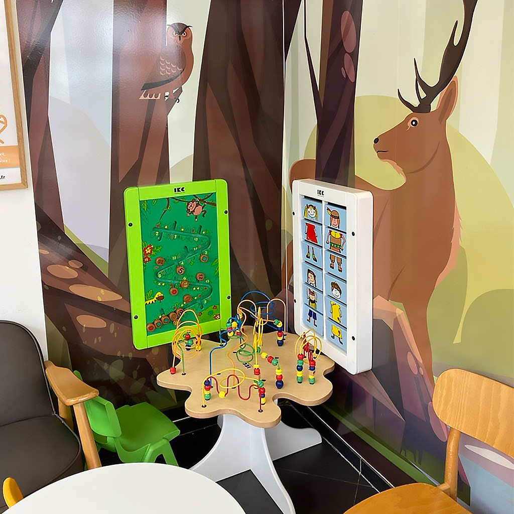 IKC-speelhoek in wachtruimte met bosdecor – spelen, ontdekken en ontspannen Kinderhoek met wandspelpanelen en kralentafel in een wachtruimte met bosdierenmuurprint. Ontworpen om kinderen op een speelse manier bezig te houden terwijl ouders ontspannen.